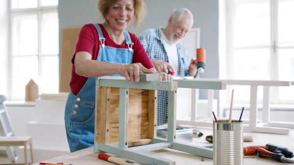 Beautiful senior couple renovating old wooden furniture.