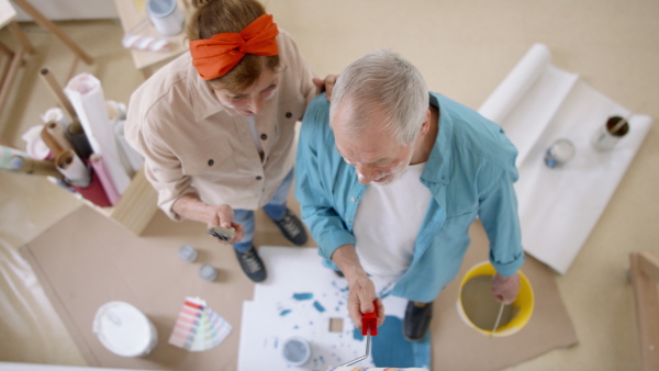 A top view of senior couple renovating their new flat, painting walls.