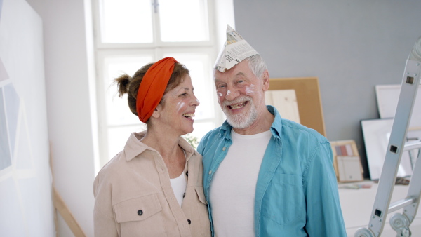 Beautiful senior couple renovating their new flat, standing and looking at camera.