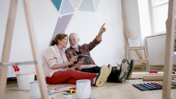 Beautiful senior couple planning the renovation of their new flat on tablet.