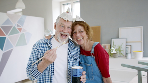 Beautiful senior couple renovating their new flat, standing and looking at camera.