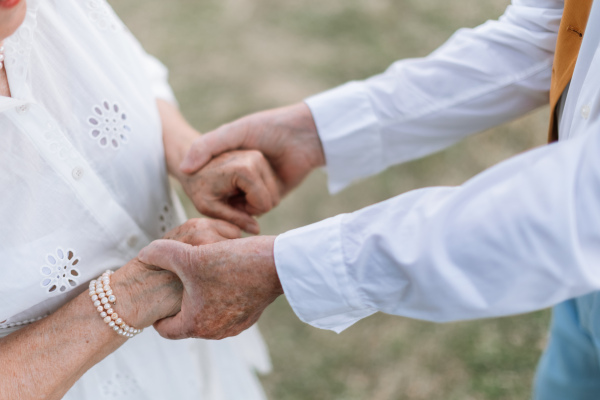 Close-up of seniors hands during their marriage in garden.