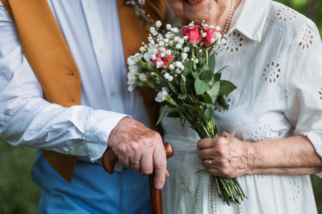 Close-up of senior hands with wedding bouquet and golden wedding rings during their marriage.