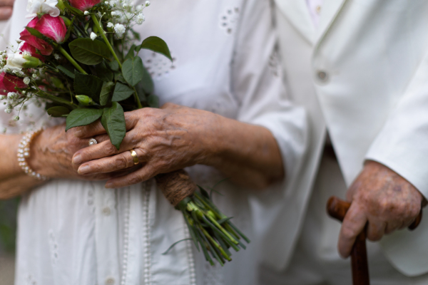 Close-up of seniors hands with golden wedding rings during their marriage.