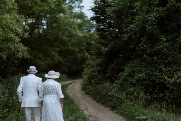 Rear view of senior couple having wedding photography in a forest during summer day.