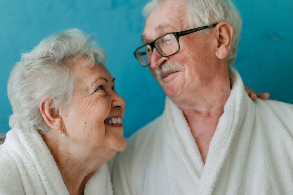 Portrait of happy senior couple sitting together in the bathrobe on sofa, having nice time at home.