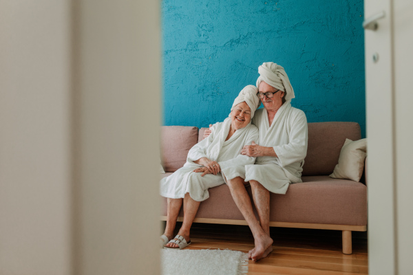 Happy senior couple sitting together in the bathrobe on sofa, having nice time at home.