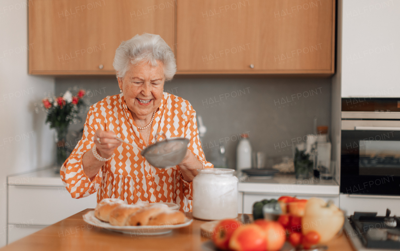 Happy senior woman sugaring homemade sweet braided bread with the raisins.