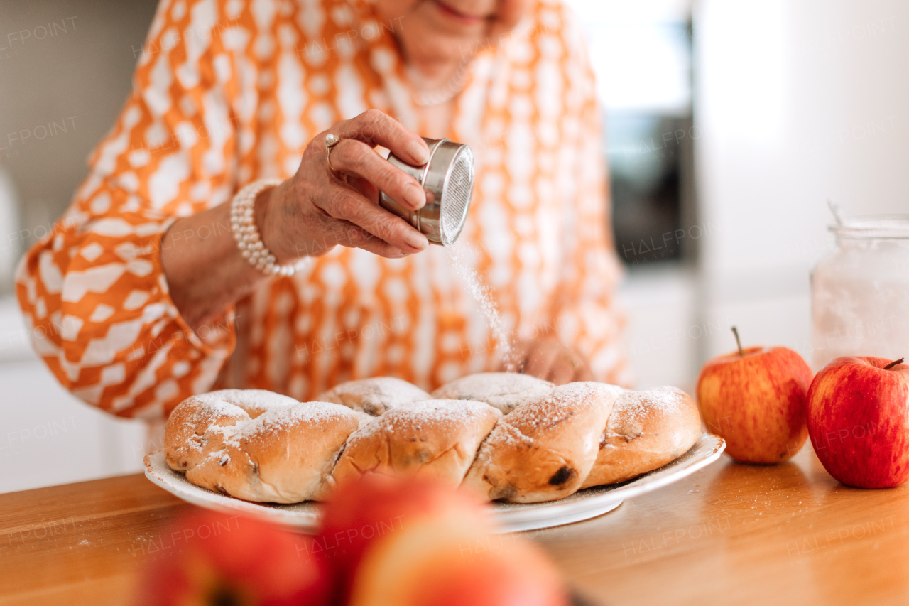 Happy senior woman holding homemade sweet braided bread with raisins. Close-up.