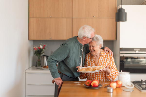 Happy senior couple holding homemade sweet braided bread with raisins.