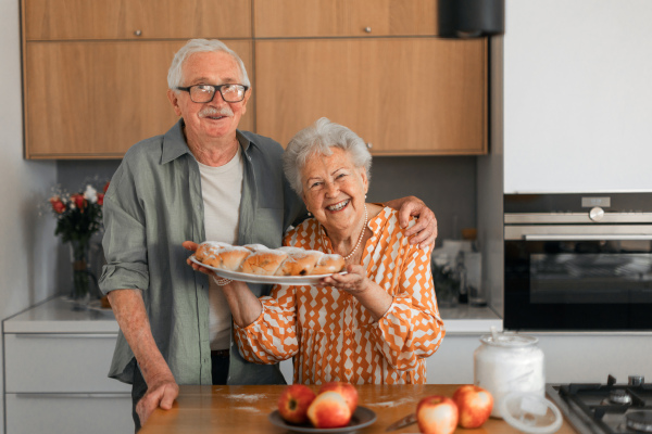 Happy senior couple holding homemade sweet braided bread with raisins.