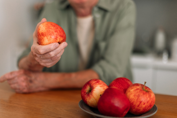 Close-up of senior man holding apples in a kitchen.