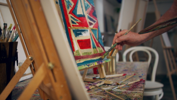 A senior man painting in an artist atelier.