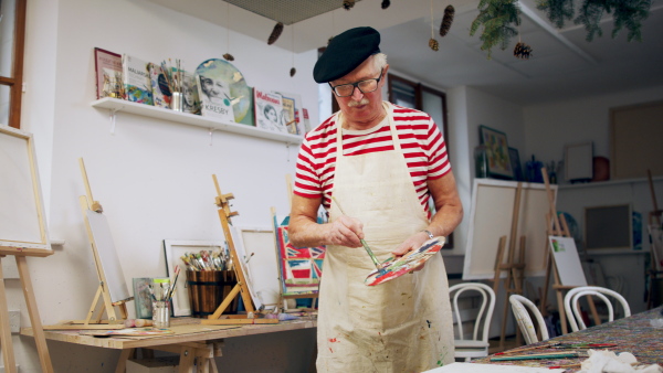 A senior man painting in an artist atelier.