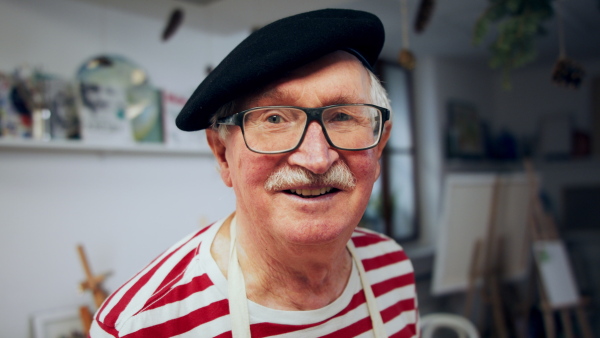 A senior man painting in an artist atelier.