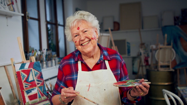 A senior woman painting in an artist atelier.