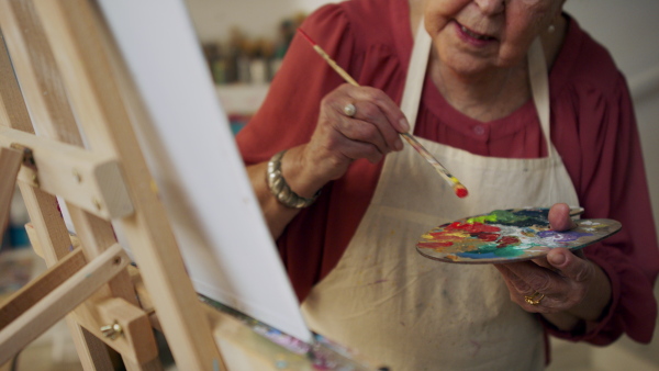 A senior woman painting in an artist atelier.