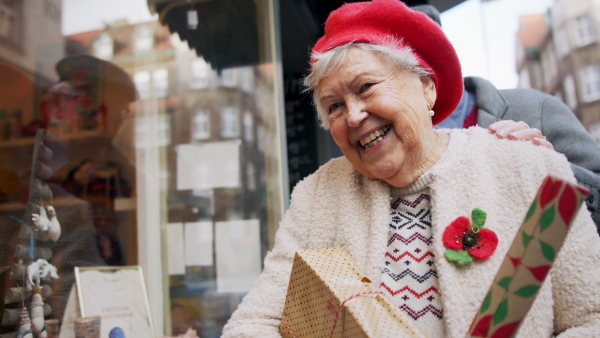 Happy senior couple at outdoor Christmas market, watching and buying a gifts and Christmas decorations.