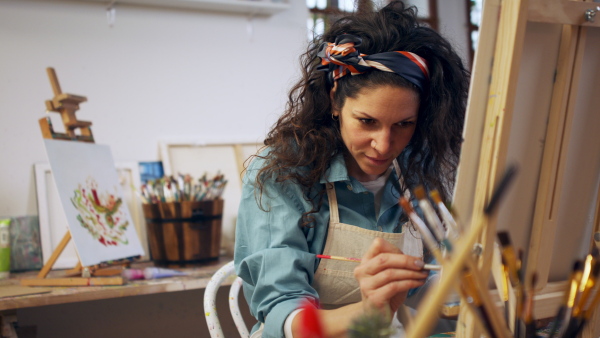 Young artis woman painting at a canvas in her atelier.