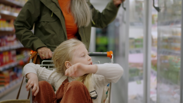 A grandmother with her granddaughter buying food in supermarket.