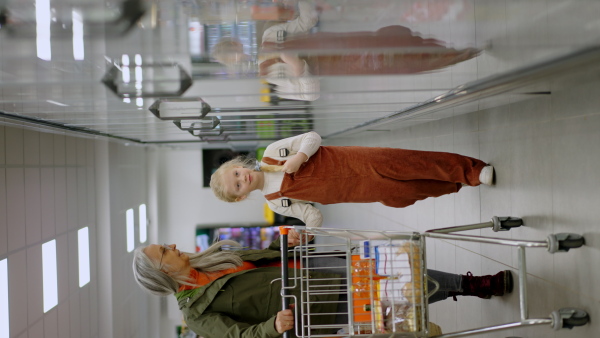 A grandmother with her granddaughter buying food in supermarket.