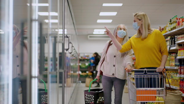 A young woman with senior mother shopping in supermarket, during pandemic