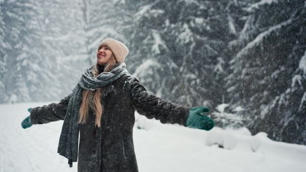 A happy young carefree woman breathing fresh air in the snowy nature.