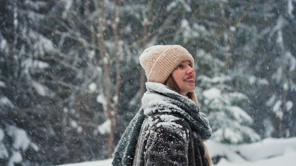 A happy young carefree woman breathing fresh air in the snowy nature.