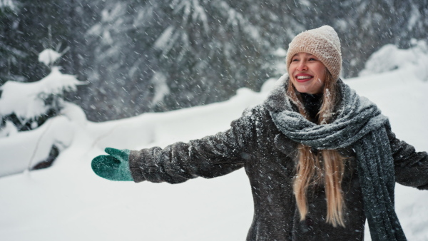 A happy young carefree woman breathing fresh air in the snowy nature.