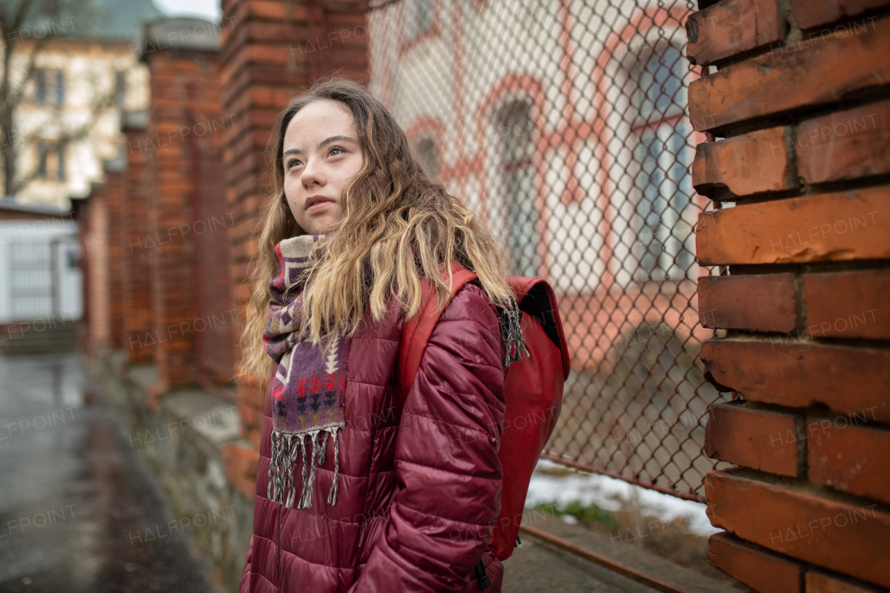 A young woman student with Down syndrome walking in street in winter