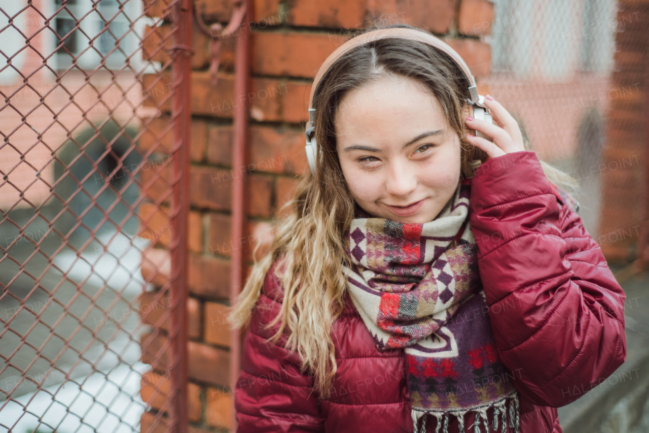 A happy young woman with Down syndrome listening to music in town in winter