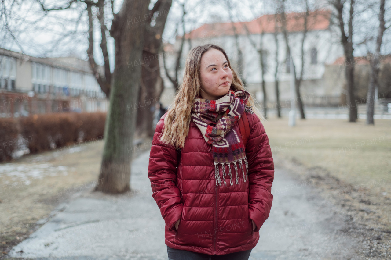 A young woman student with Down syndrome walking in street in winter