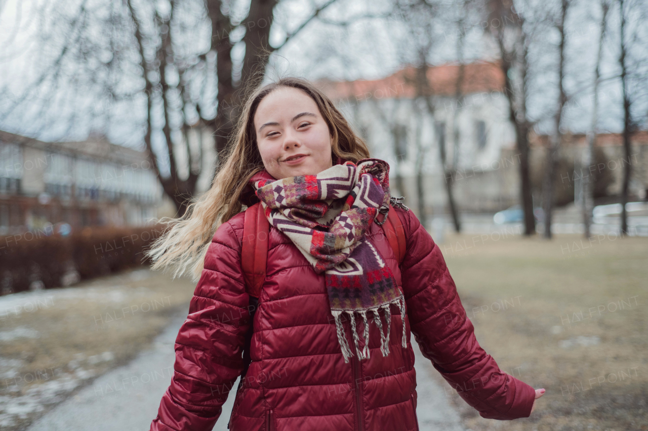 A young woman student with Down syndrome walking in street in winter