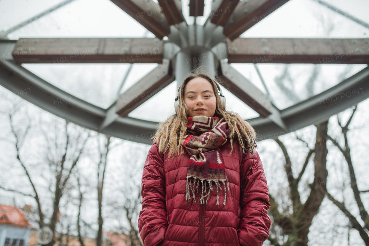 A happy young woman with Down syndrome listening to music in town in winter