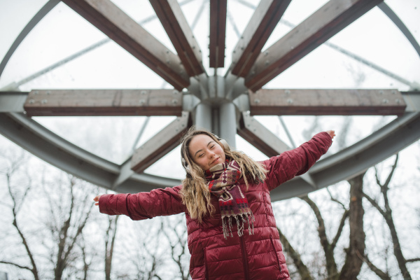 A happy young woman with Down syndrome listening to music in town in winter