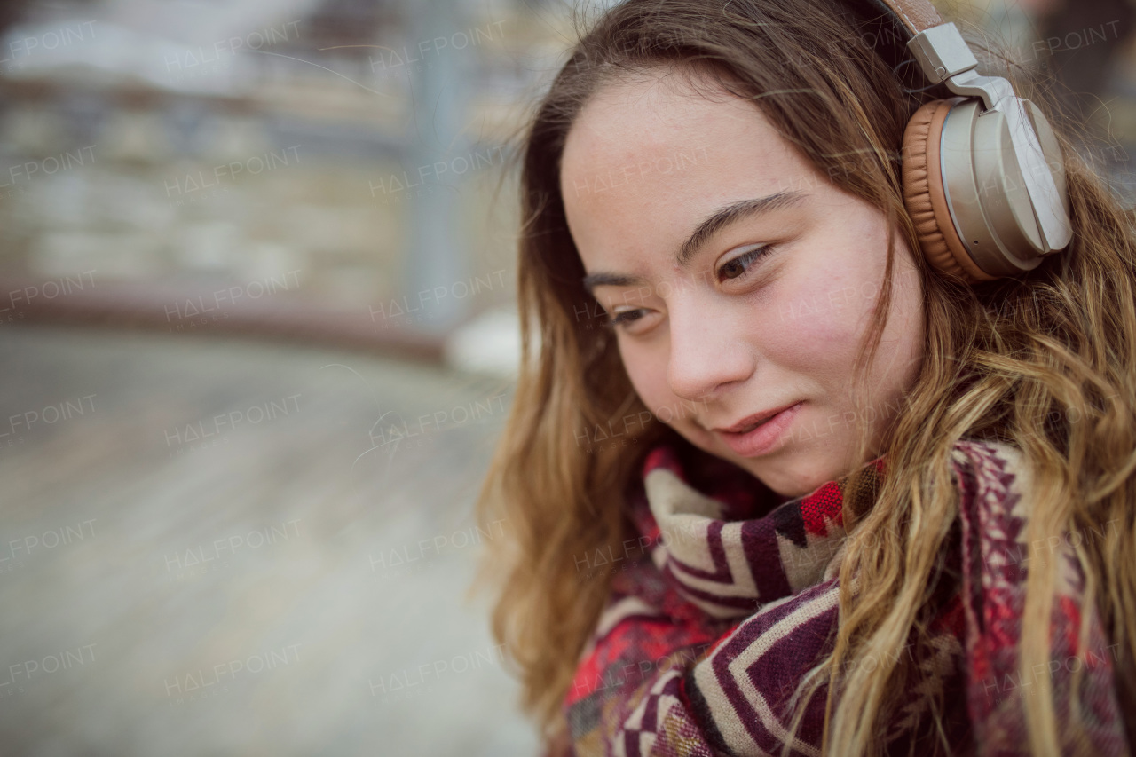 A happy young woman with Down syndrome listening to music in town in winter