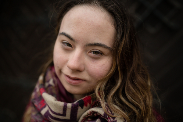 A close-up of young woman with Down syndrome looking at camera on black background