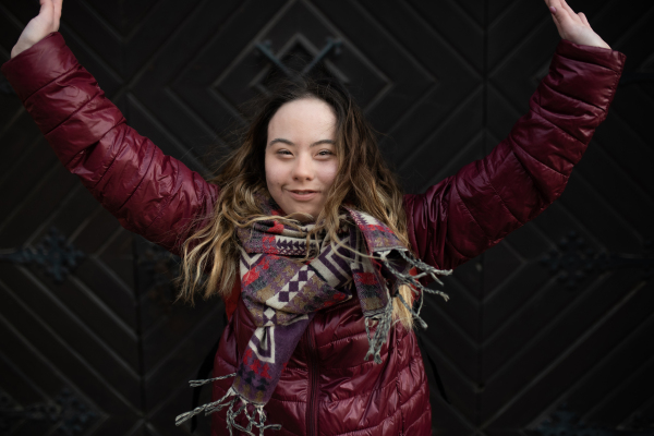 A happy young woman with Down syndrome with raised arms in town in winter