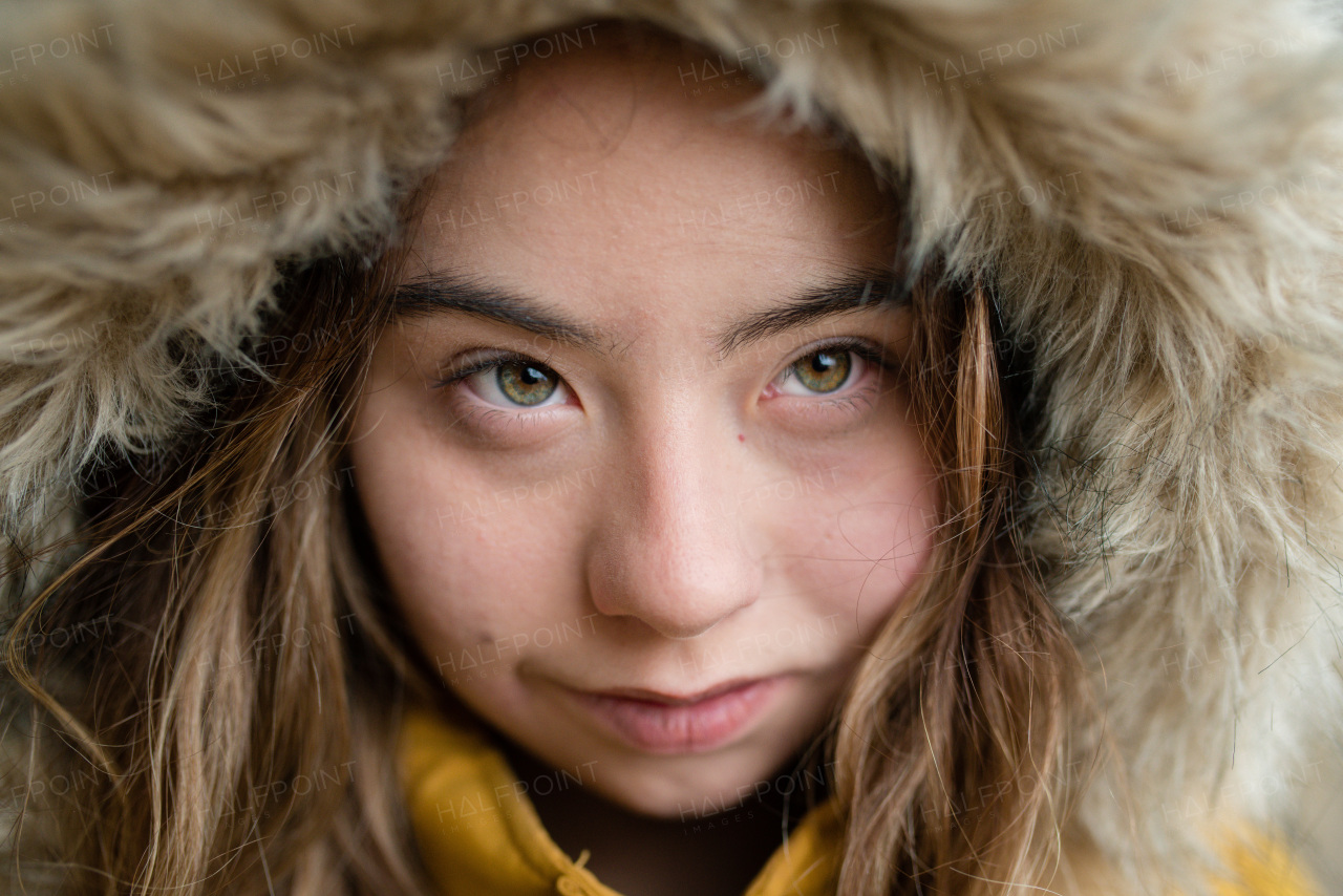 A close-up of young woman with Down syndrome weraing hood and looking at camera