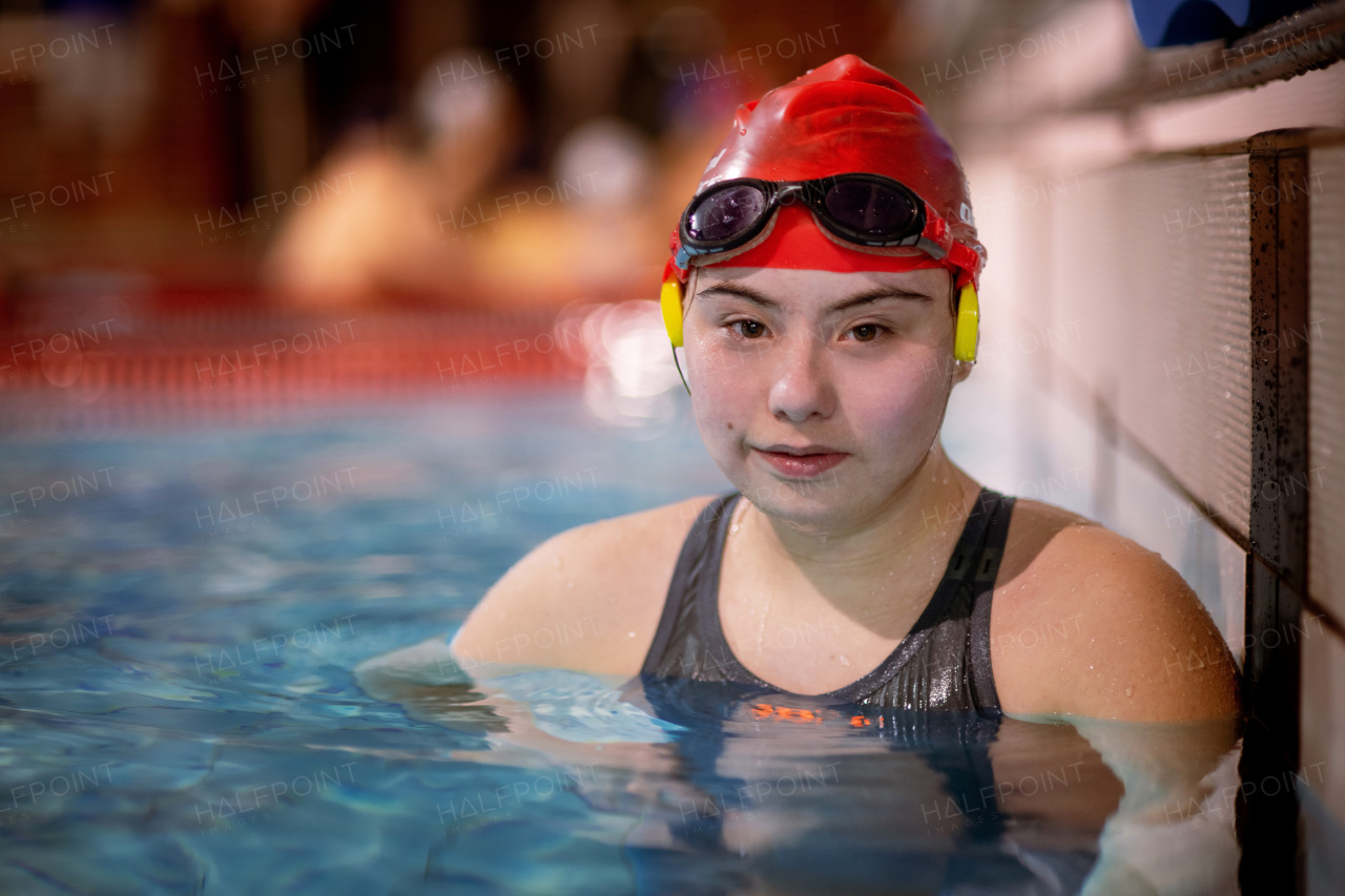 A young woman with Down syndrome in swimming pool looking at camera