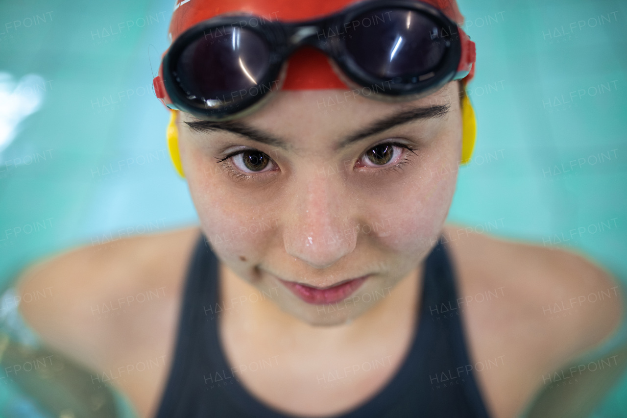 A young woman with Down syndrome in swimming pool looking at camera