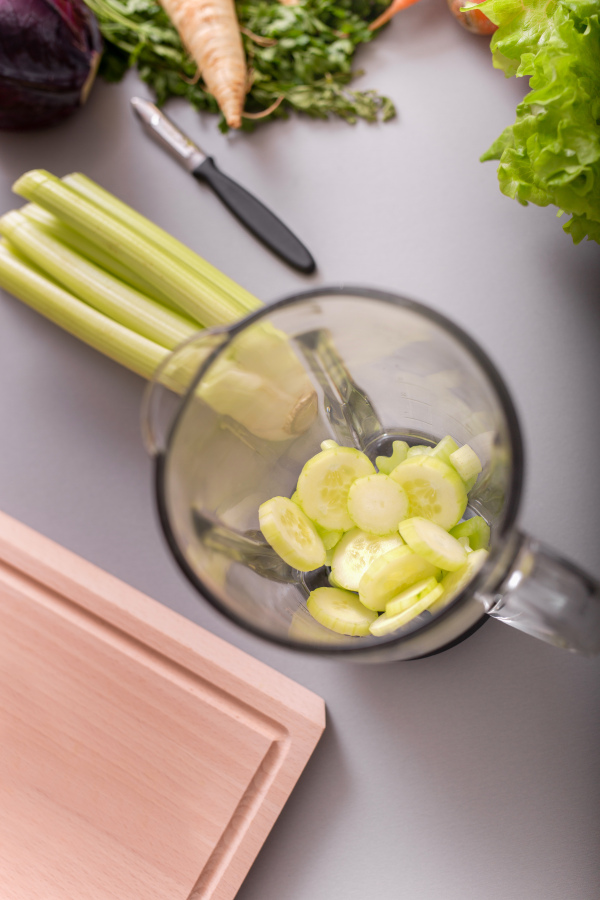 Raw cucmbers and cellery in a blender ready to make fresh homemade smoothie. Healthy lifestyle concept