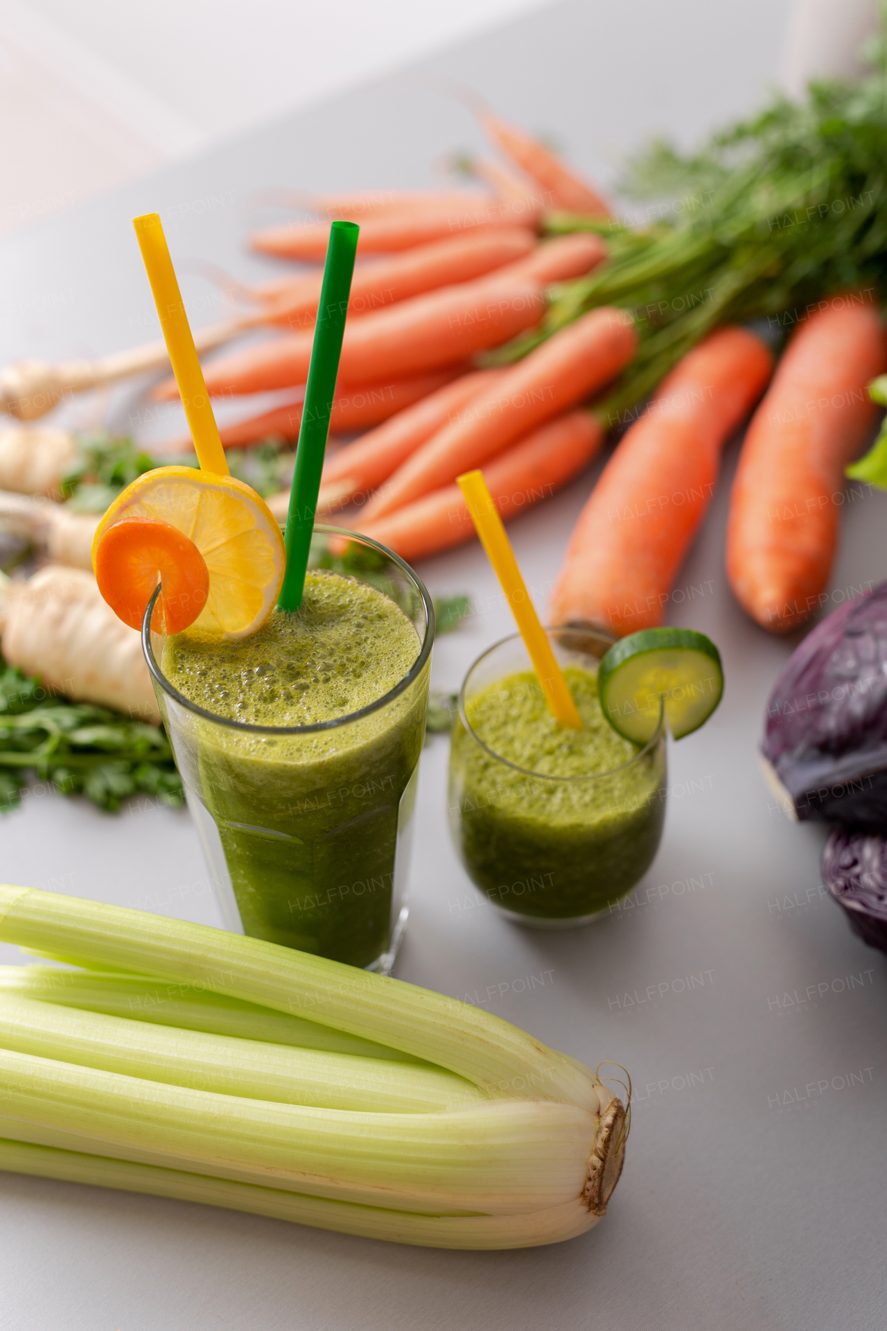 A green smoothie in glass with straw and cucumber and vegetagbles at background, detox, vegan, vegetarian healthy vegetable drink