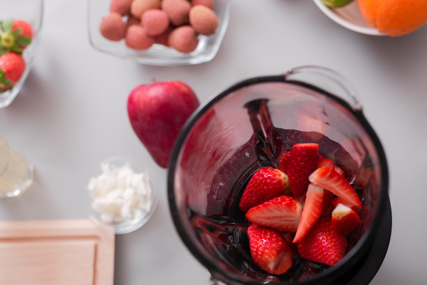 Raw strawberries in a blender ready to make fresh homemade smoothie. Healthy lifestyle concept