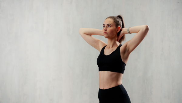 A sports woman in fashion black sport clothes posing in gym, over gray background