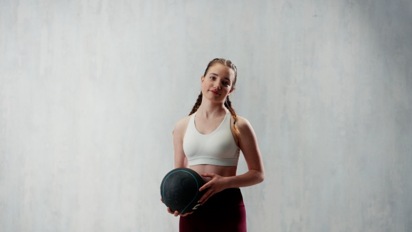 An athletic fitness woman working out with medicine ball on grey background. Copy space.