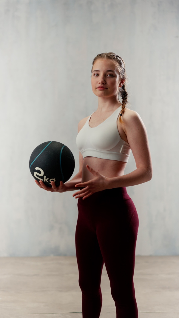 An athletic fitness woman working out with medicine ball on grey background. Copy space.