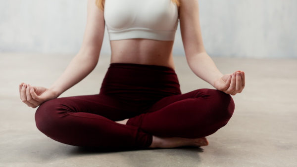 A young healthy woman in black sportsclothes practising yoga in studio, in a yoga position, copy space