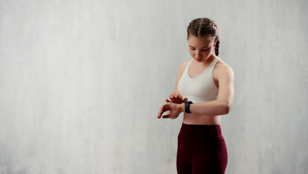 A young woman setting and looking at sports smartwatch. Fitness female checking her performance.