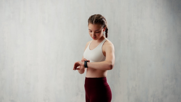 A young woman setting and looking at sports smartwatch. Fitness female checking her performance.